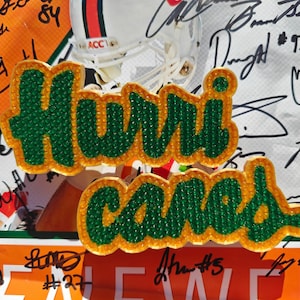 Könnte beinhalten: Grüne und gelbe Filzpatches mit den Worten "Hurricanes" in einer Blasenschrift. Die Patches sind mit kleinen grünen und gelben Perlen verziert.