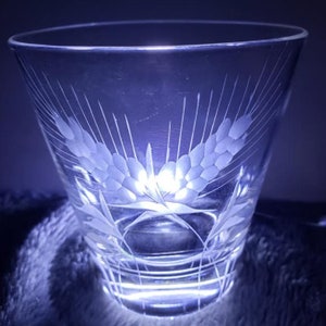 May include: A clear glass with an etched design of wheat stalks. The glass has a wide mouth and a rounded bottom.