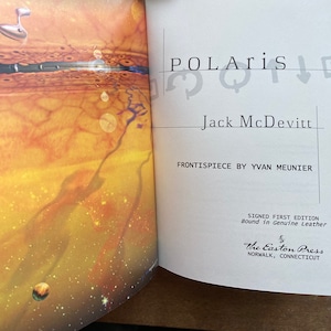 May include: An open book titled "Polaris" by Jack McDevitt with a colorful illustration on the front cover. The book is a signed first edition bound in genuine leather and published by The Easton Press in Norwalk, Connecticut.