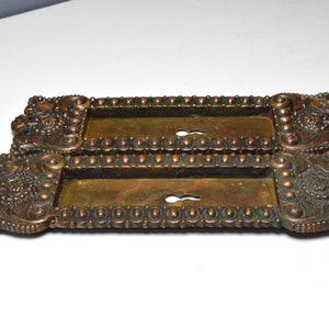 May include: Two antique brass door plates with ornate designs and keyholes. The plates have a beaded border and intricate floral patterns.