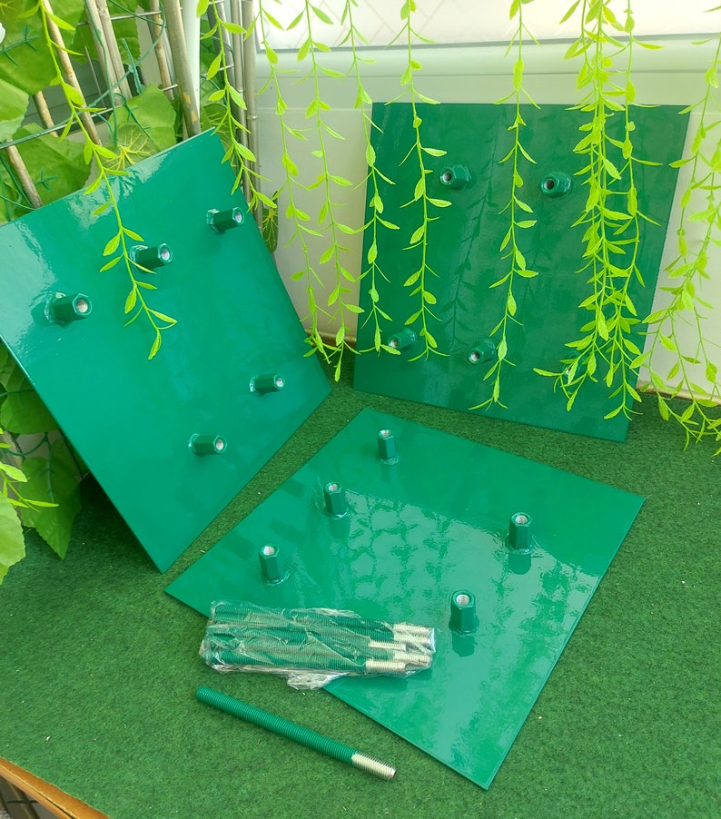 May include: Three green metal square plates with multiple metal posts, likely for a garden structure. A bundle of metal rods and a single rod are also present. The plates are a glossy green color, and the background includes greenery.