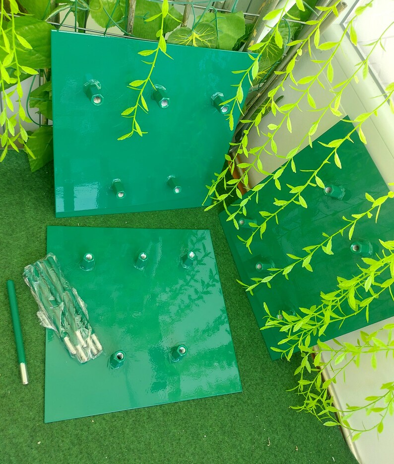 May include: Three square, bright green metal plates with six bolt holes each. A bundle of bolts and a green rod are next to one of the plates. The plates are arranged on a green surface with green leafy vines in the background.