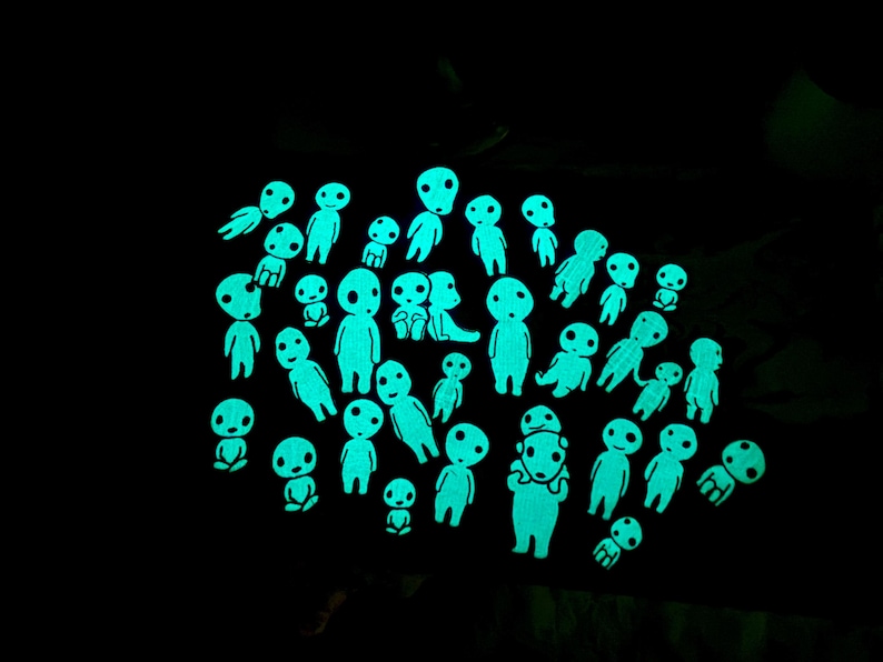 May include: A collection of numerous small, glow-in-the-dark figures arranged against a solid black background. Each figure features a smooth, rounded head with simple facial features, emitting a bright cyan light in the darkness.