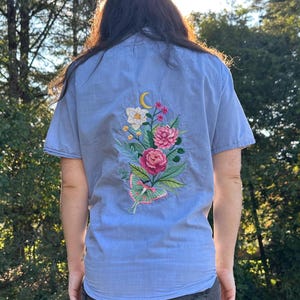 May include: A white ceramic mug with a black handle and the text "But First, Coffee" in a black, handwritten-style font. The mug is on a white surface.