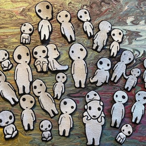 Puede incluir: Una colección de parches bordados con espíritus Kodama de la película de animación La Princesa Mononoke. Los parches están en varias poses y tamaños, con un color beige claro y contornos negros. El fondo es un patrón abstracto colorido.