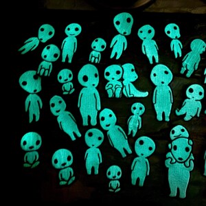 May include: A collection of numerous small, glowing cyan figures with rounded heads and simple facial features arranged against a dark background. Each figure displays a distinct posture, with some standing, sitting, or leaning, all emitting a bright light.