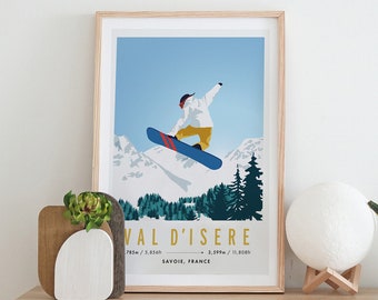 May include: A framed poster with a blue sky and mountains in the background. A person is snowboarding in the air. The poster says "Val d'Isere" with the text "781m / 2,562ft - 3,599m / 11,808ft Savoie, France".