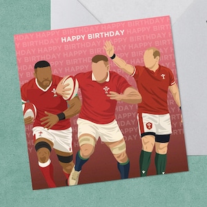 May include: A birthday card featuring three rugby players in red jerseys, with the text "HAPPY BIRTHDAY" in a repeating pattern. The card is inside a white envelope, with a black pen on the side.