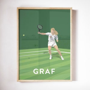 May include: A framed print featuring a tennis player in action on a green court. The player, dressed in white, is mid-swing with a black racket. The word "GRAF" is printed in white block letters below the player.