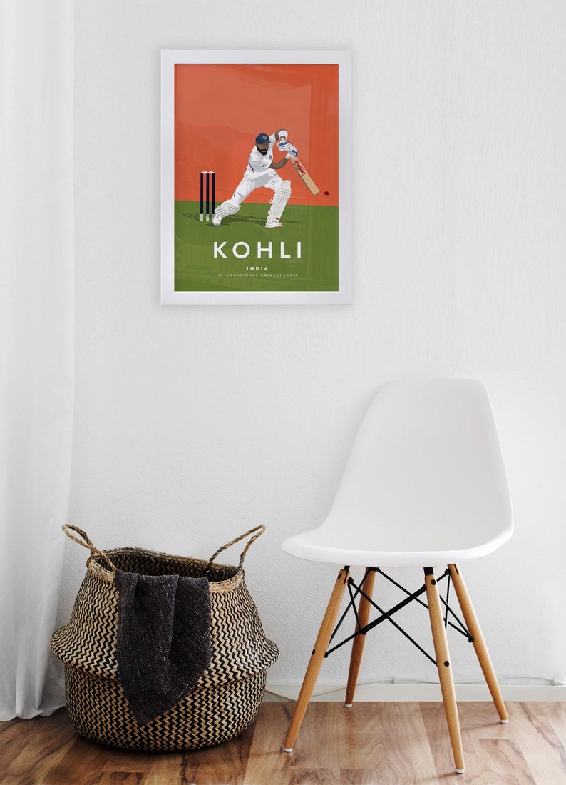 Pode incluir: Um p&ocirc;ster emoldurado com fundo branco e uma ilustra&ccedil;&atilde;o laranja e verde de um jogador de cr&iacute;quete em a&ccedil;&atilde;o. O p&ocirc;ster tem o texto "KOHLI" em letras pretas e "India" em letras pretas menores abaixo. O texto "INTERNATIONAL CRICKET.COM" est&aacute; em letras pretas ainda menores abaixo de "India".