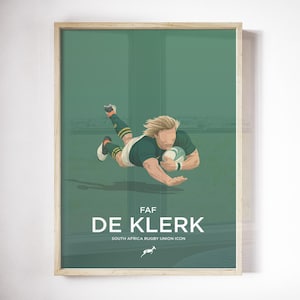 Puede incluir: Impresión enmarcada que representa a un jugador de rugby lanzándose con un balón, vistiendo un uniforme verde y dorado. La impresión incluye el texto "FAF DE KLERK" y "SOUTH AFRICA RUGBY UNION ICON" con un logotipo de springbok, sobre un fondo verde.