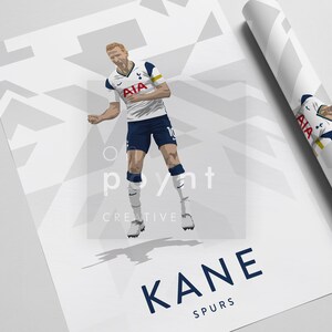 Pode incluir: Uma camisa de futebol branca e azul com um logotipo branco e azul no peito. A camisa tem o texto "AIA" na frente. O jogador est&aacute; vestindo shorts azuis e meias brancas. O jogador est&aacute; no ar com os bra&ccedil;os levantados. O fundo &eacute; branco com um padr&atilde;o geom&eacute;trico. O texto "KANE" e "SPURS" est&aacute; na parte inferior da imagem.