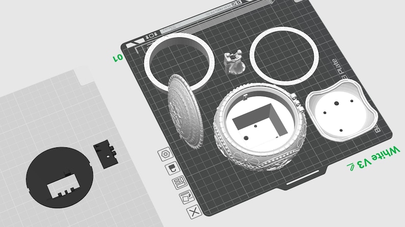 May include: A 3D printed model of a decorative box with a hinged lid. The box is made up of several pieces, including a base, lid, and decorative elements. The model is printed in white plastic and is shown on a black grid.