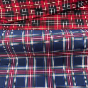 May include: Two rolls of fabric featuring plaid patterns. The top roll displays a red, black, and white tartan design with thin gold metallic lines. The bottom roll features a navy blue, red, green, and white plaid pattern with gold metallic accents.