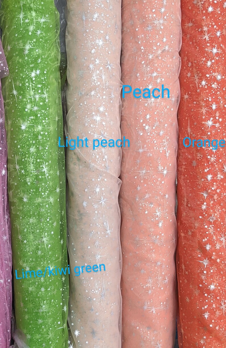 May include: Four rolls of sheer fabric with silver glitter stars printed on them. The fabric colors are lime green, light peach, peach, and orange.
