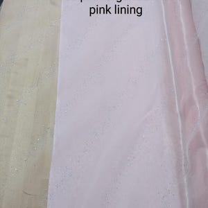 May include: Pale pink organza fabric with a pink lining. The fabric has a shimmering, glittery effect. The text on the image reads "Ice pink organza with pink lining."