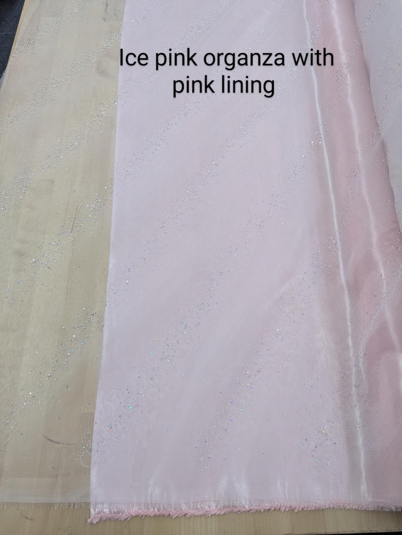 May include: Pale pink organza fabric with a pink lining. The fabric has a shimmering, glittery effect. The text on the image reads "Ice pink organza with pink lining."