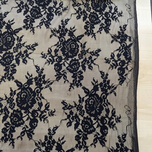 May include: Black lace fabric with a floral pattern. The lace is delicate and has a sheer appearance.