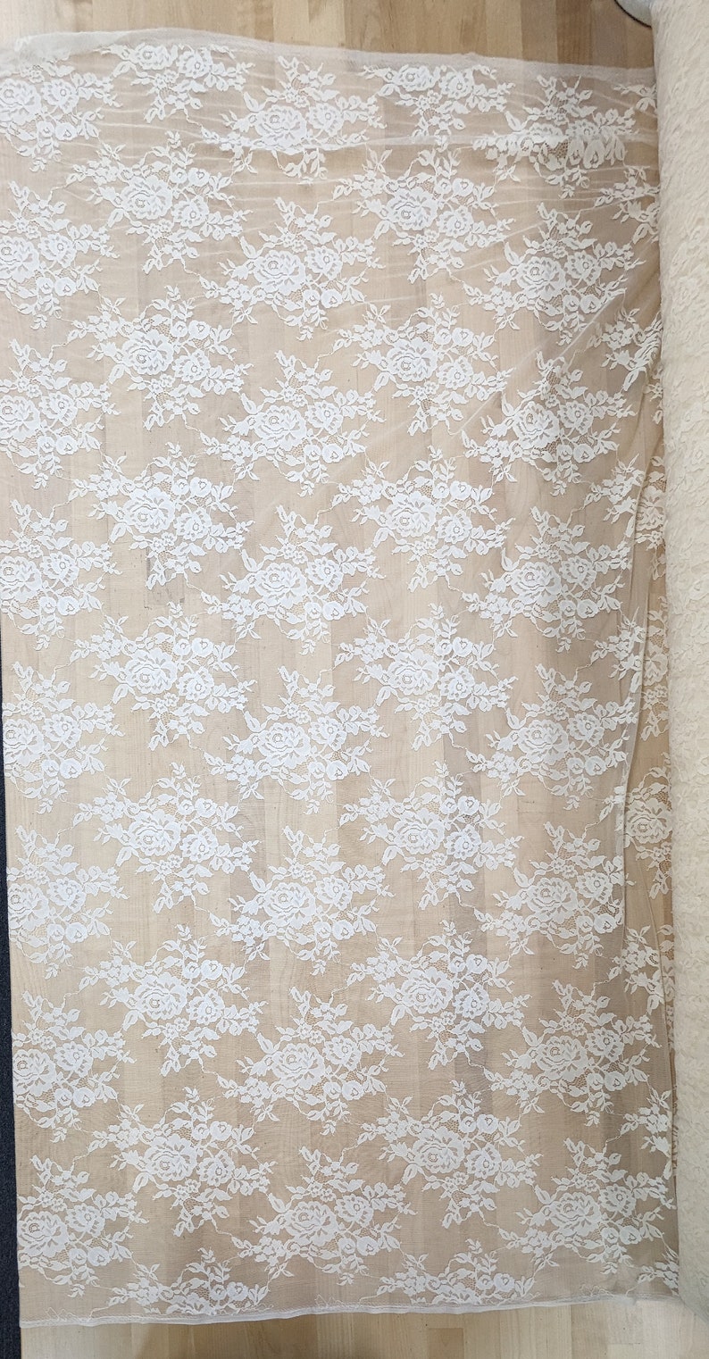 May include: White lace fabric with a floral pattern. The lace is delicate and sheer, with a soft, flowing texture.