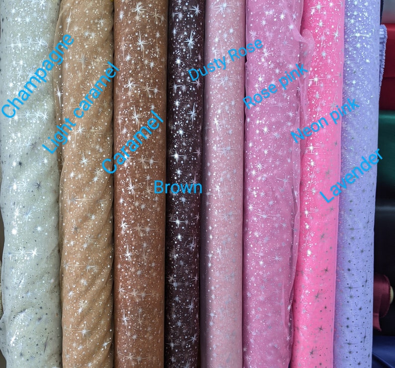 May include: Rolls of sheer fabric with a star pattern in various colors, including champagne, light caramel, caramel, brown, dusty rose, rose pink, neon pink, and lavender.