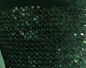 May include: Dark green velvet fabric with a layer of black sequins. The sequins are arranged in a pattern that resembles fish scales.