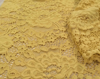 May include: A close-up of yellow lace fabric with a delicate floral pattern.