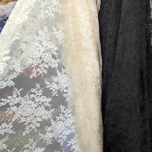 May include: Two pieces of lace fabric, one white and one black, with a floral pattern. The white lace is sheer and delicate, while the black lace is more opaque and has a more pronounced floral design.