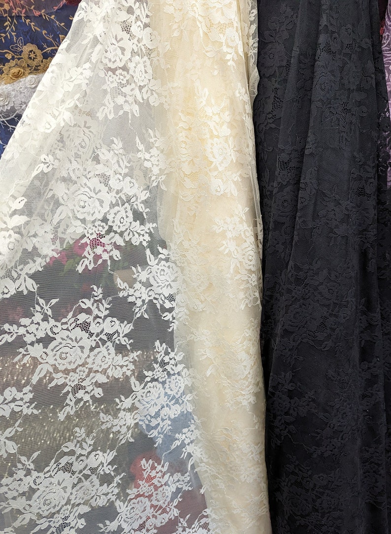 May include: Two pieces of lace fabric, one white and one black, with a floral pattern. The white lace is sheer and delicate, while the black lace is more opaque and has a more pronounced floral design.