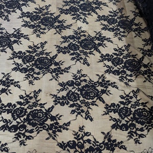 May include: Black lace fabric with a floral pattern. The lace is delicate and has a soft, flowing texture.