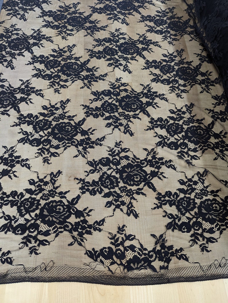 May include: Black lace fabric with a floral pattern. The lace is delicate and has a soft, flowing texture.