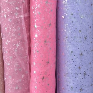 May include: Three rolls of sheer fabric with a silver star pattern. The fabric is pink, light pink, and lavender.