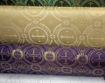 May include: Close-up of several rolls of fabric with repeating cross and floral patterns. Colors include teal, gold, purple, and white. The fabric appears to be a brocade or damask, suitable for liturgical or decorative purposes.