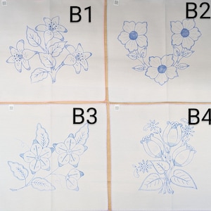 May include: Four white embroidered linen squares with different blue floral designs. B1 features a branch of flowers, B2 has three flowers, B3 shows flowers and leaves, and B4 displays a bouquet of tulips.