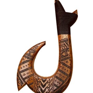 May include: A wooden fish hook with intricate carvings in a brown and black pattern. The hook is attached to a black cord.