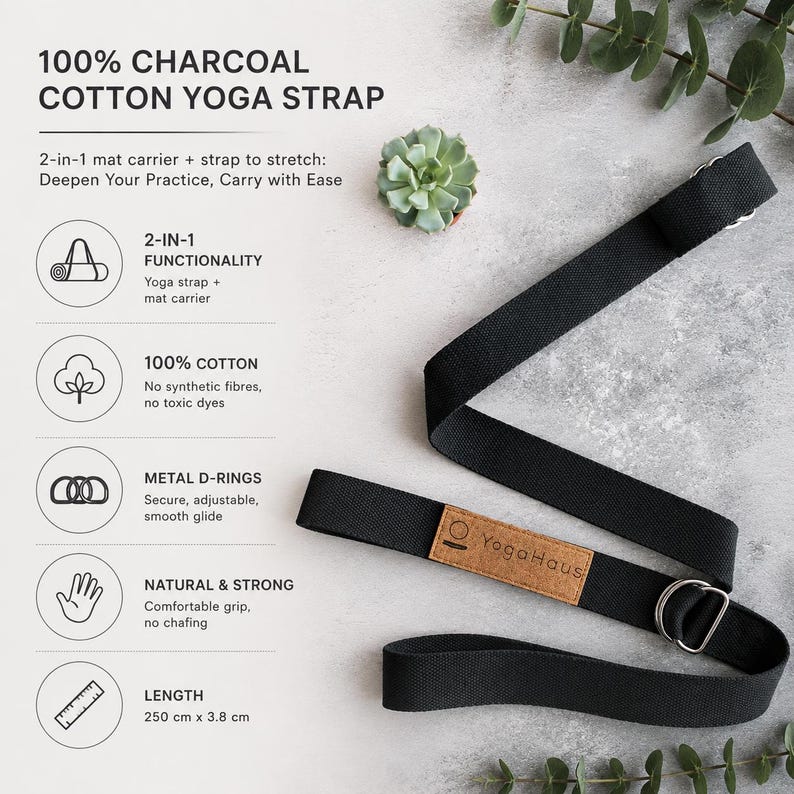 May include: A charcoal cotton yoga strap with metal D-rings and a natural, comfortable grip. The strap is 250 cm long and 3.8 cm wide. The text on the strap reads "Yoga Haus".