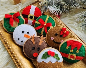 May include: A set of eight felt Christmas decorations shaped like gingerbread cookies. The decorations are decorated with festive details like holly, bows, and candy canes.  The decorations are displayed on a gold tray.