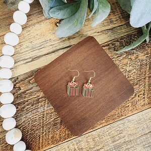 May include: A pair of gold-tone earrings featuring a red, green and white gift box design.