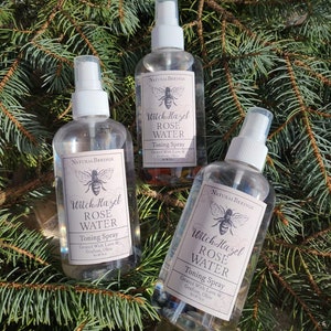Puede incluir: Tres botellas de vidrio transparente con pulverizadores blancos y etiquetas. Las etiquetas son blancas con texto negro que dice "Witch Hazel Rose Water Toning Spray" y "Creado con amor en Grafton, Ohio".