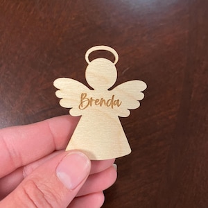 May include: A wooden angel ornament with a halo and wings, personalized with the name "Brenda".