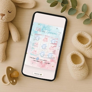 May include: A smartphone displays a baby shower game with the text "Fille ou Garcon?" in pink and blue. The image includes a plush bunny, a pacifier, and a pair of knitted baby booties. The game features illustrations of baby clothes.
