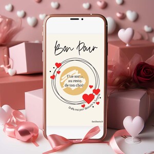Peut inclure: Un smartphone affiche un bon cadeau avec l'inscription "Bon Pour" et "Une sortie au resto de ton choix" en écriture noire. Des cœurs rouges et un cercle ornent le texte. Le téléphone est posé devant des boîtes cadeaux roses et des décorations en forme de cœur.