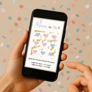 Può includere: Uno smartphone mostra un gioco di rivelazione del sesso con cuori rosa e blu. Il testo "Garçon ou Fille?" è in alto. Le istruzioni indicano che i cuori blu rivelano un maschio, quelli rosa una femmina.