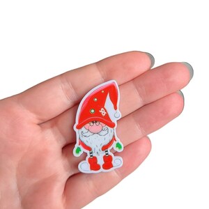 May include: A red and white gnome with a white beard and a red hat with white trim. The gnome is wearing red boots and has green mittens.