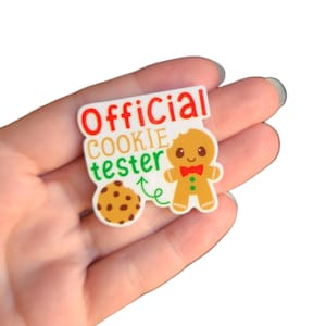 May include: White sticker with the text "Official Cookie Tester" in red, green, and black lettering. A gingerbread man with a red bow tie and a brown cookie are pictured on the sticker.