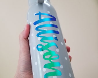 May include: A gray water bottle with white polka dots and a blue and green iridescent vinyl decal that says "Mommy".