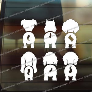 May include: White vinyl car decal featuring the rear ends of seven different dog breeds. The decals are arranged in two rows, showcasing the dogs' tails and rear ends. The image is set against a car window.