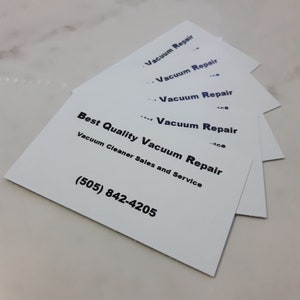 May include: A stack of white business cards with black text. The top card reads "Vacuum Repair" and the bottom card reads "Best Quality Vacuum Repair, Vacuum Cleaner Sales and Service (505) 842-4205".