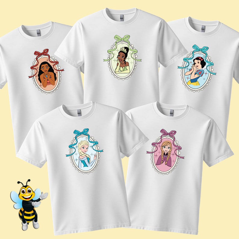 Puede incluir: Camisetas blancas con retratos de dibujos animados de princesas de Disney en marcos ovalados. Cada camiseta muestra una princesa diferente, enmarcada por una cinta y un borde de encaje. Las camisetas se muestran sobre un fondo amarillo claro.