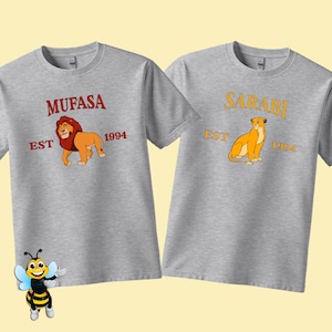 May include: Two grey t-shirts with a lion and lioness graphic. The text on the shirts reads "Mufasa Est 1994" and "Sarabi Est 1994".