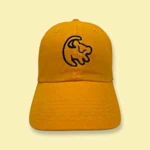 May include: A yellow baseball cap with a black embroidered lion paw print logo.